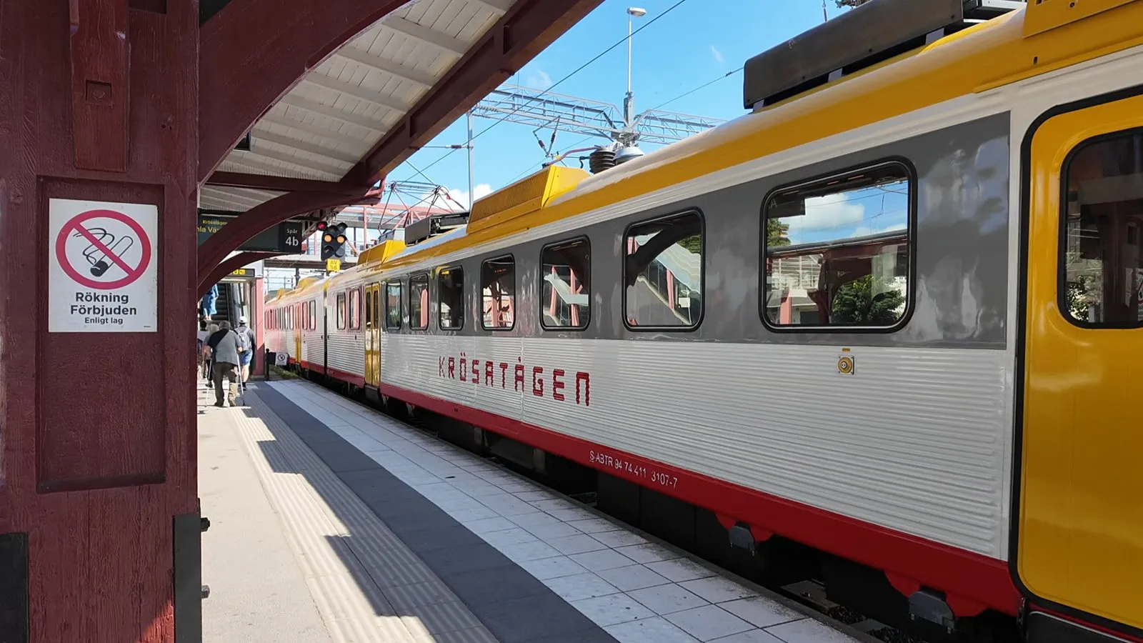 乗り換えの駅のホーム。赤い木の柱の向こうに、黄色と赤の普通列車が止まる